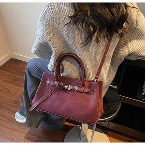 Deep red matte leather tote bag detail with decorative buckle strap and long shoulder strap