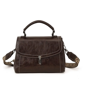 Retro dark brown crossbody bag with wide woven strap and white stitching on white backdrop
