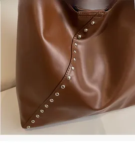 Detailed close-up of dark brown faux leather bag with silver metal rivet decorations