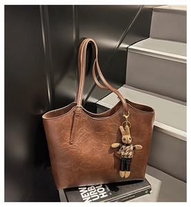 Detail of dark brown leather tote bag with vintage texture and cute bunny charm on a book