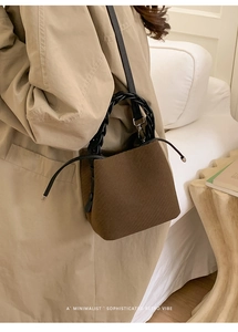 Close-up of brown textured bucket bag with woven handle and drawstring detail