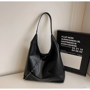 Close-up of black matte hobo bag with diagonal silver rivet studs and single strap