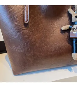 Detail of dark brown tote bag featuring retro pleated texture and beige rabbit charm