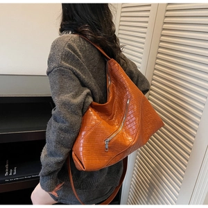 Detail of large orange woven shoulder bag showing tight texture and metal zipper