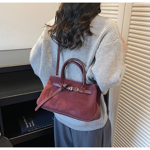 Burgundy matte leather tote bag carried by model wearing a grey knit sweater for commuting