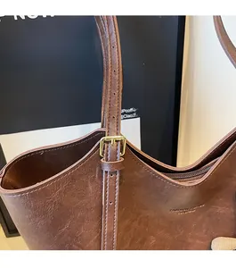 Detail of adjustable strap with gold-tone buckle on a dark brown leather tote bag