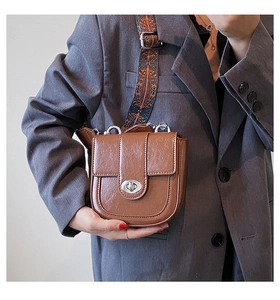 Détail du sac selle marron vintage avec bandoulière tissée géométrique et fermoir argenté