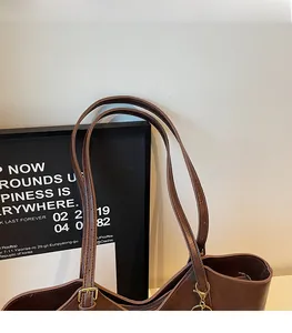 Detail of adjustable slender strap and metal buckle on dark coffee vintage tote bag