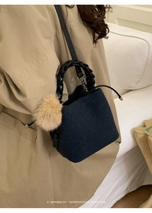 Detail of wool bucket bag with woven handle and plush charm on a beige trench coat