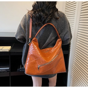 Detail of orange woven tote bag showing premium PU texture and slanted zipper design