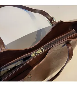 Detailed macro shot of smooth gold metal zipper and leather texture on brown tote bag