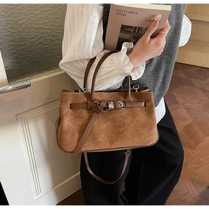 Macro detail of retro brown matte leather tote bag featuring buckle straps and knotted accents