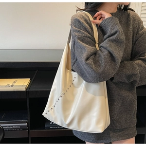Detail of cream hobo bag with silver metal studs on soft PU leather material