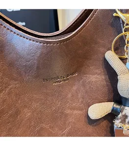 Macro detail of brown leather tote with vintage texture, gold hardware, and bunny charm