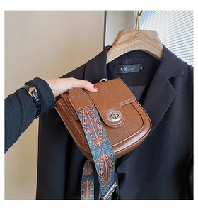 Détail du sac en cuir marron avec bandoulière tissée ethnique colorée et fermoir rotatif