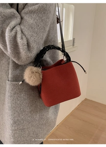 Detail of red bucket bag with woven handle and plush charm in a minimalist retro vibe