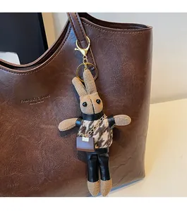 Detail of a handmade knitted rabbit charm with houndstooth vest on a leather tote bag