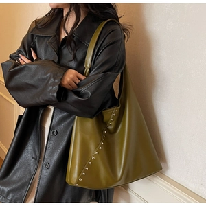 Detail of olive green tote bag featuring silver studs and premium matte leather texture