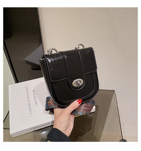 Détail du petit sac carré noir brillant avec une large bandoulière de style bohème colorée