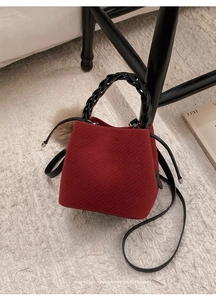 Detail of red tweed bucket bag with woven handle and fluffy pompom charm accessory