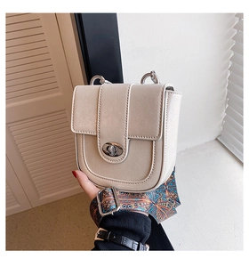 Détail de sac bandoulière beige avec une large sangle à imprimé bohème et boucle en métal
