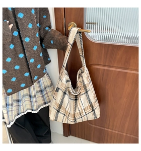 Detail der Vintage-Karo-Einkaufstasche mit schwarzem Webetikett auf strukturiertem Stoff