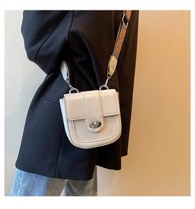 Détail d'un sac bandoulière beige avec large sangle ethnique et fermoir métallique argenté