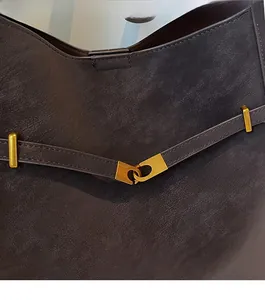 Detail of dark brown vintage suede bag featuring durable gold metal buckle and rivets