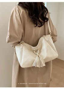 Detail of off-white leather hobo bag with fringe pendant and woven stitching accents
