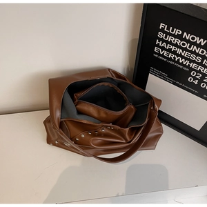 Detail of dark brown tote bag showing the inner pouch and silver rivet studs