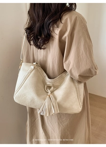 Minimalist beige tote bag featuring vintage fringe detail and gold metal hardware ring