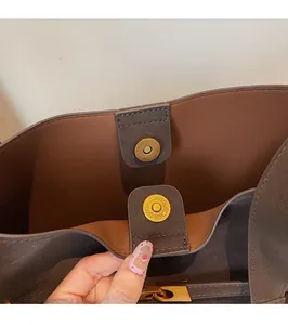 Macro view of a secure golden magnetic buckle on a vintage brown faux suede shoulder bag