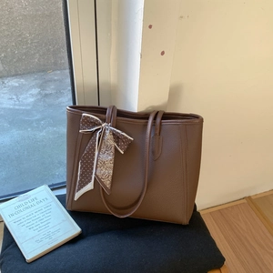 Minimalist coffee brown pebbled leather tote bag with a patterned silk scarf on the handle