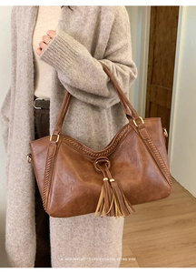 Close-up of retro brown tote bag featuring long tassel charms and hand-woven edge details