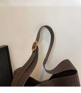 Detail of dark brown leather strap with a vintage golden oval buckle on a tote bag