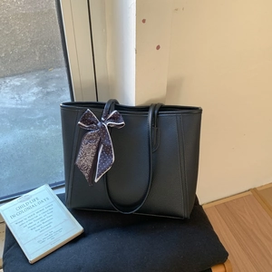 Minimalist black lychee texture tote bag with a patterned silk scarf bow detail