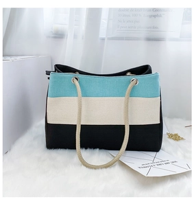 Detailaufnahme der dreifarbigen Canvas-Tasche mit Hanfseilgriffen auf einem Plüschteppich