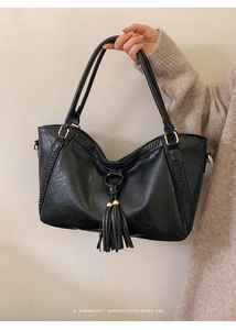 Detail of black faux leather tote with long fringe tassel and gold hardware accents