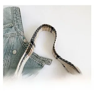 Detail der karierten Webgriffe an einer Retro-Stofftasche mit Denim-Styling