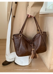 Detail of retro dark brown tote bag with tassels, woven stitching and gold hardware