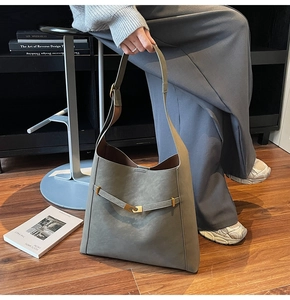 Macro detail of large dark grey faux suede tote bag with golden buckle and sleek matte finish