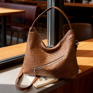 Brown woven leather hobo bag with large capacity and dual shoulder straps in a cafe setting