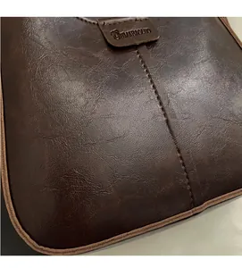 Close-up of vintage brown leather bucket bag with brand label and textured stitching