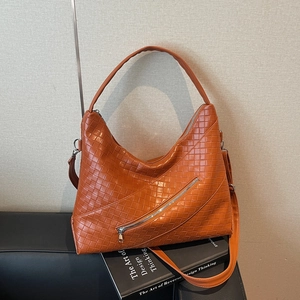 Orange woven hobo bag with zipper detail and adjustable strap on a book background