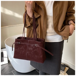Detail of burgundy suede tote bag featuring decorative straps and vintage metal hardware