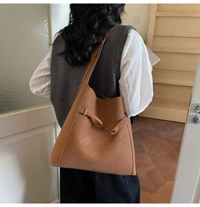 Detail view of brown matte faux suede tote bag featuring adjustable strap and metal buckle