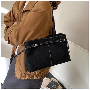Close-up of black suede tote bag with white contrast stitching and buckle detail