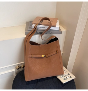 Detail of a brown faux suede tote bag with adjustable strap and gold metal buckle