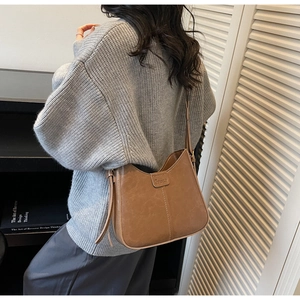Detail view of vintage brown matte leather bucket bag with embossed strap on a model