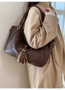 Brown vintage leather tote bag detail with fringe tassel and woven sides on model